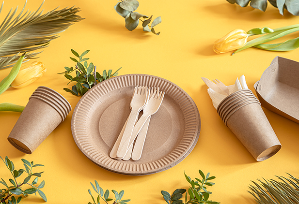 Eco-friendly, stylish recyclable paper tableware. Paper food boxes, plates, and cornstarch Cutlery on a trending orange background.